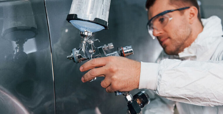 a man wearing goggles and white coat holding a spray gun